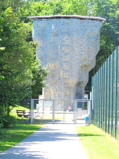 Kletterturm umgeben von Bäumen und einem Zaun mit Eingangstor